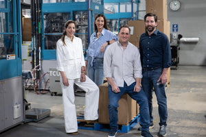 Four people posing in a warehouse setting with industrial equipment.